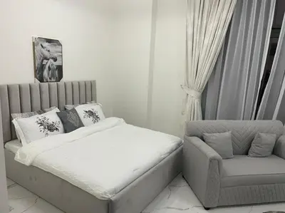 a white bedroom with a bed and a chair at Luxury & Comfort in Majan A Dubai Delight in Dubai