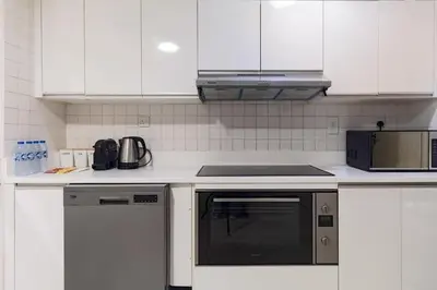 a kitchen with white cabinets and a black appliance at Luxury stay Private Beach Access in Dubai