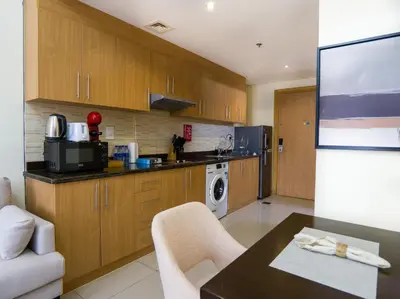 a kitchen with wooden cabinets and a washer and dryer at EasyGo -Stylish STU With pool view Linkin park Arjan- 17 in Dubai