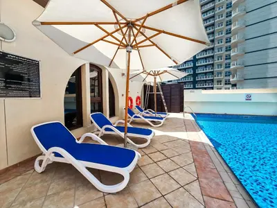 a pool with lounge chairs and an umbrella and a swimming pool at EasyGo -Stylish STU With pool view Linkin park Arjan- 17 in Dubai