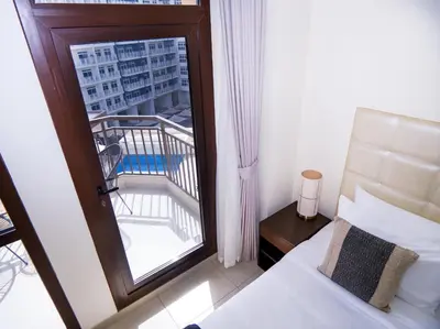 a bedroom with a bed and a window with a balcony at EasyGo -Stylish STU With pool view Linkin park Arjan- 17 in Dubai
