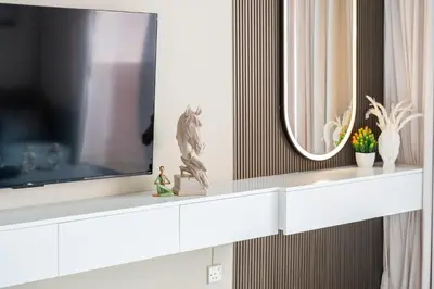 a living room with a tv on a white shelf at Sunny Studio Perfect For Discovery Gardens Stays in Dubai
