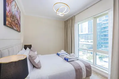a white bedroom with a bed and a window at Luxurious Waterfront at Al Majara Dubai Marina in Dubai