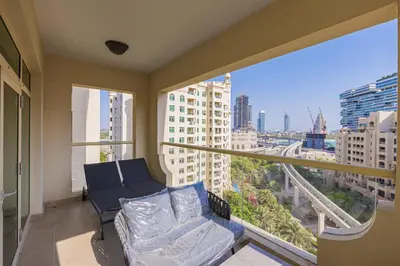 a living room with a couch and a large window at DVH Al Hamri Jumeirah Shoreline 2 Bed & Maids Free beach access in Dubai