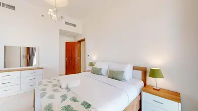 a white bedroom with a large bed and a lamp at Vacationer I Sophisticated 1 Bedroom Apartment I Steps from Dubai Mall & Burj Khalifa I Dunya Tower in Dubai