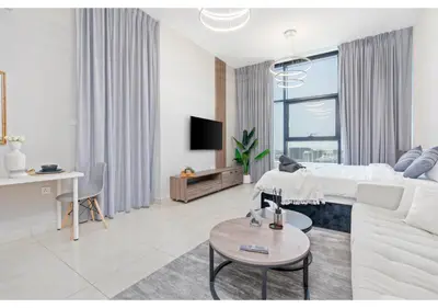 a white living room with a white couch and a table at Bright Resort Style Studio Amenities Samana GA by Vibel in Dubai