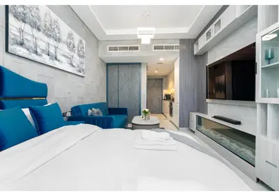 a bedroom with a large white bed and blue chairs at Bright Resort Style Studio Amenities Samana GA by Vibel in Dubai