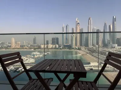 a table and chairs on a balcony with a view of a city at 2 Bed - Sunrise Bay Views in Dubai