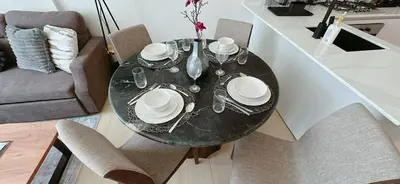 a dining room table with chairs and a black table with plates at Comfortable 1br Stay In Jvc Parking & Pool in Dubai