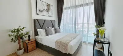a bedroom with a bed and a large window at Comfortable 1br Stay In Jvc Parking & Pool in Dubai