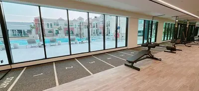 a large room with a gym with windows and a pool at Comfortable 1br Stay In Jvc Parking & Pool in Dubai