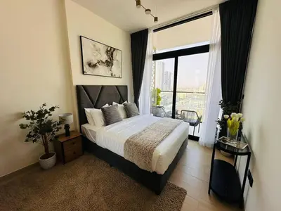 a bedroom with a bed and a large window at Comfortable 1br Stay In Jvc Parking & Pool in Dubai