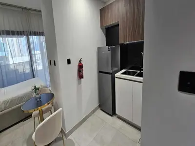 a small kitchen with a table and a refrigerator at Luxury Studio in Jumeirah Village Circle in Dubai