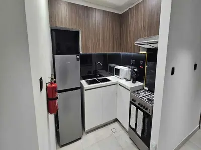 a kitchen with a refrigerator and a sink and a stove at Luxury Studio in Jumeirah Village Circle in Dubai