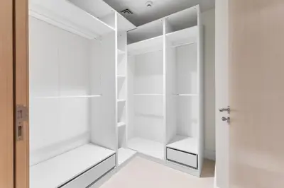 a white walk in closet with white cabinets at Full Fountain and Burj View - 3BR Burj Royale in Dubai