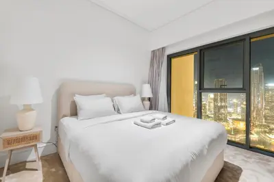 a white bedroom with a large bed and a window at Full Fountain and Burj View - 3BR Burj Royale in Dubai