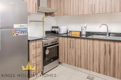 a kitchen with wooden cabinets and a stainless steel refrigerator at Royal suites Dunya tower Burj Khalifa St Kings in Dubai