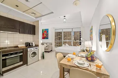 a kitchen and living room with a table and chairs at FIRST CLASS Studio Cozy Urban Retreat in Dubai