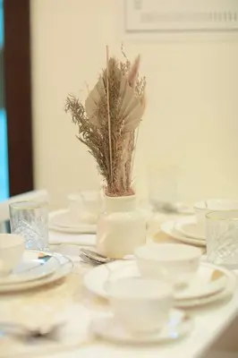 a table with white plates and a vase with a plant at 2BR - LUXE Serene Suite by Canal in Dubai