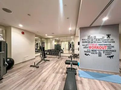 a gym with a wall with a sign and weights at 2BR - LUXE Serene Suite by Canal in Dubai