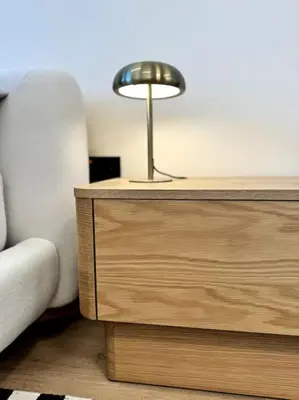a lamp on top of a wooden dresser next to a couch at Brand New Studio - Comfy & WFH in Dubai