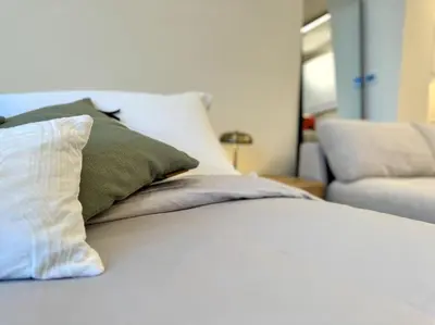 a white bed with several pillows and a couch at Brand New Studio - Comfy & WFH in Dubai