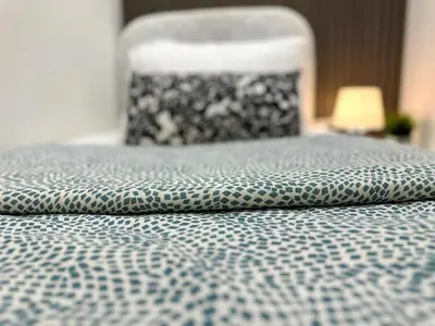 a bed with a black and white bedspread and a chair at Atelier Partition Room in Tecom Near Internet City Metro in Dubai