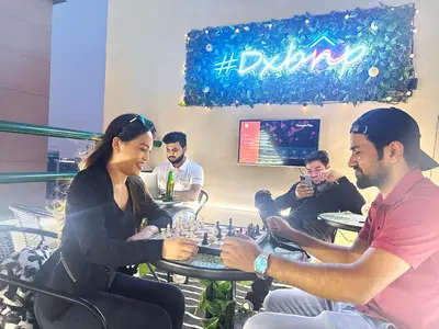 a group of people sitting around a table playing chess at Nomad Partition Room in Barsha Heights 3 mins to ICM Metro in Dubai