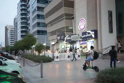 a woman riding a scooter in front of a building at Nomad Partition Room in Barsha Heights 3 mins to ICM Metro in Dubai