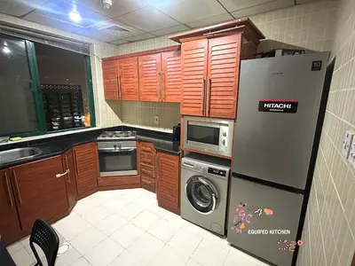 a kitchen with wooden cabinets and a refrigerator at Quiet Partition Room in Tecom Barsha Heights in Dubai