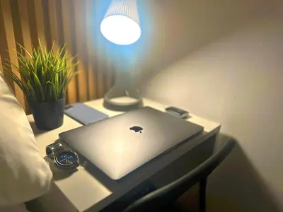 an apple laptop sitting on a desk next to a lamp at Quiet Partition Room in Tecom Barsha Heights in Dubai