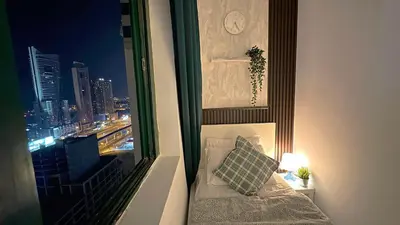 a bedroom with a view of a city at night at Metropolis View Partition Room Near Internet City Metro in Dubai