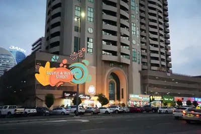 a large building with cars parked in a parking lot at Metropolis View Partition Room Near Internet City Metro in Dubai