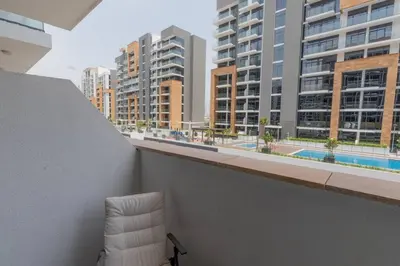 a white chair sitting on top of a balcony with buildings at Cozy Studio in Azizi Riviera - Dubai in Dubai