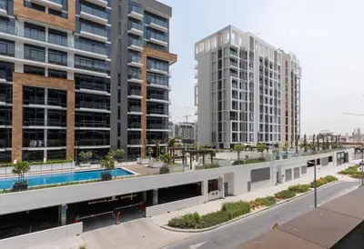 a building with a swimming pool and two tall buildings at Cozy Studio in Azizi Riviera - Dubai in Dubai