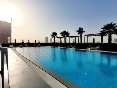 a swimming pool on top of a building with palm trees at Studio in Bloom Height - JVC - Dubai in Dubai