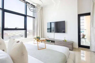 a white bedroom with a large bed and a tv at Frank Porter - Square Tower in Dubai