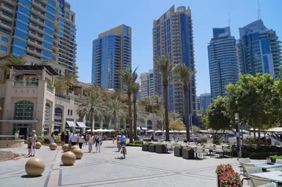 people walking and biking in a city with tall buildings at Bright & Serene Flat in the Marina, by Only Stays in Dubai