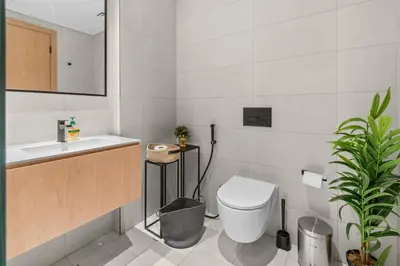 a white bathroom with a toilet and a sink at Waves - Chic High-Floor Studio Retreat with Canal Views in Dubai