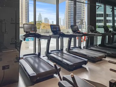 a row of treadmills in a gym with a view at Waves - Chic High-Floor Studio Retreat with Canal Views in Dubai