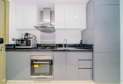 a white kitchen with a sink and a microwave at Royalton - Damac Maison Prive in Dubai