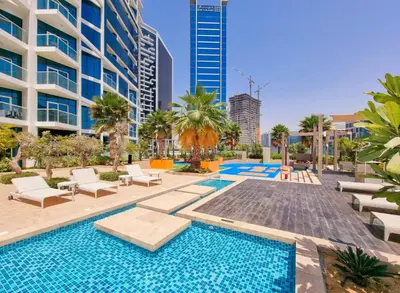 a swimming pool with chairs and a building at Royalton - Damac Maison Prive in Dubai