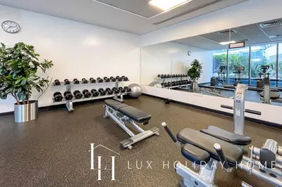 a gym with rows of exercise equipment and a row of mirrors at LUX The Silverene Marina View Studio 1 in Dubai