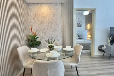 a dining room with a glass table and chairs at Elegant 1BR Midtown Near City Center Meaisem by Vibel in Dubai