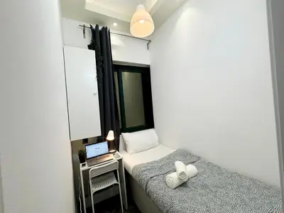 a small room with two beds and a laptop on a table at Explorer Partition Room with window Near Internet City in Dubai