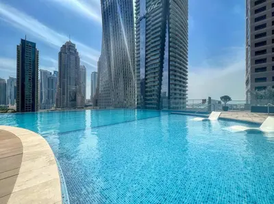 a large swimming pool in a city with tall buildings at Dubai Marina 1BR with Pool Near Shops & Restaurants in Dubai