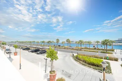 a view of a parking lot with palm trees and the ocean at LUX The Elegant Sea View Suite in Dubai