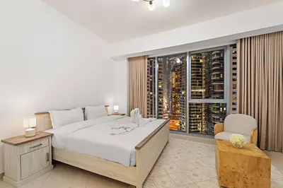 a bedroom with a large white bed and a window at FIRST CLASS 2BR Luxurious Escape in Dubai