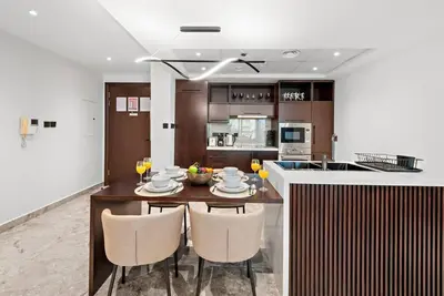 a kitchen with a wooden table with chairs and a counter at FIRST CLASS 2BR Premium City Escape in Dubai