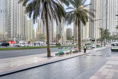 a street with palm trees in a city with tall buildings at Blueground Downtown BK view pool gym DXB-130 in Dubai
